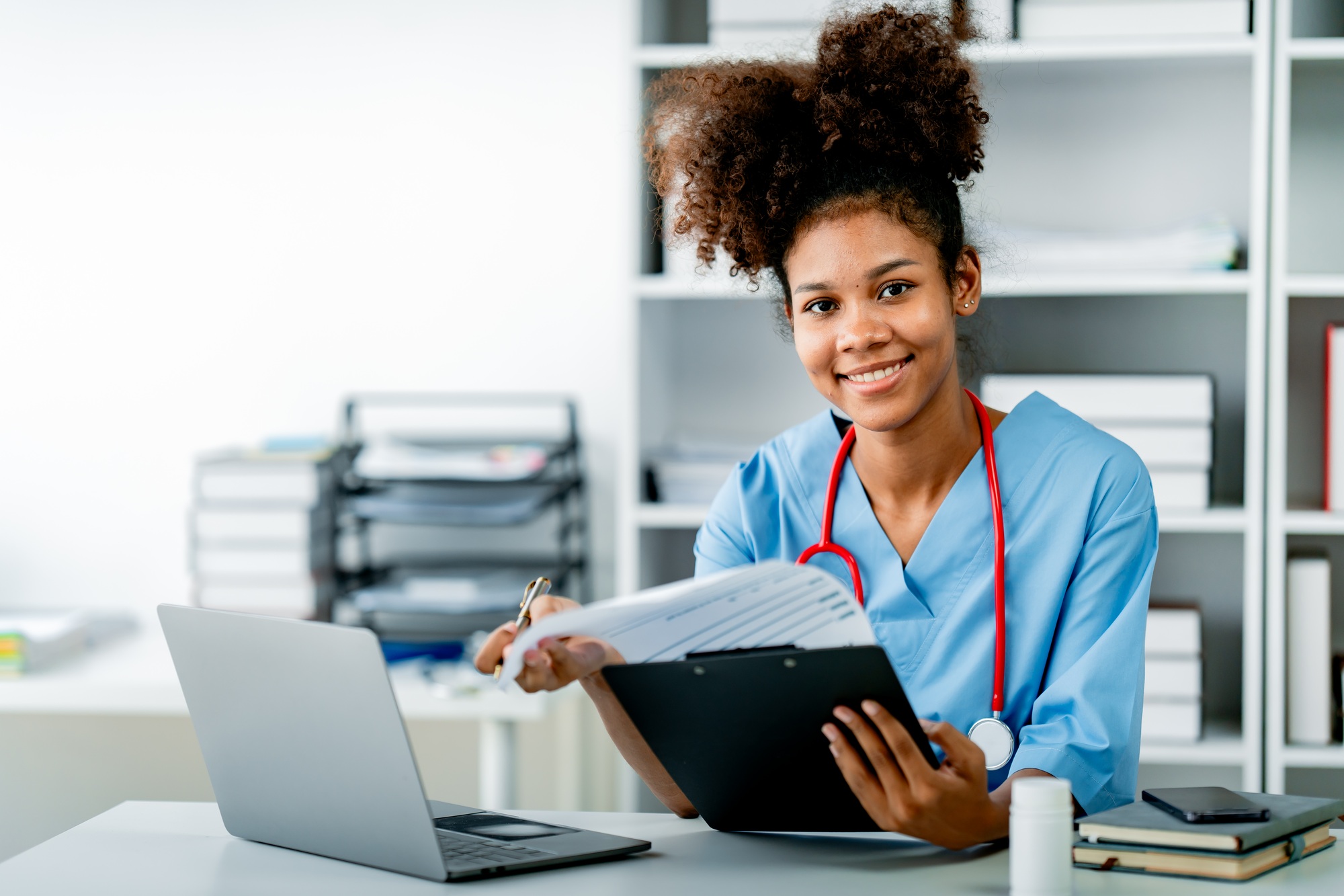 African american female doctor working on laptop, filling out paperwork, patient medical history, re